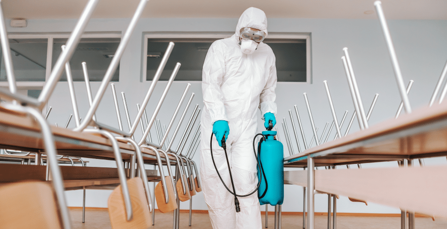 40aff4d5-man-sterile-uniform-with-gloves-mask-holding-sprayer-spraying-with-disinfectant-floor-classroom-1.png